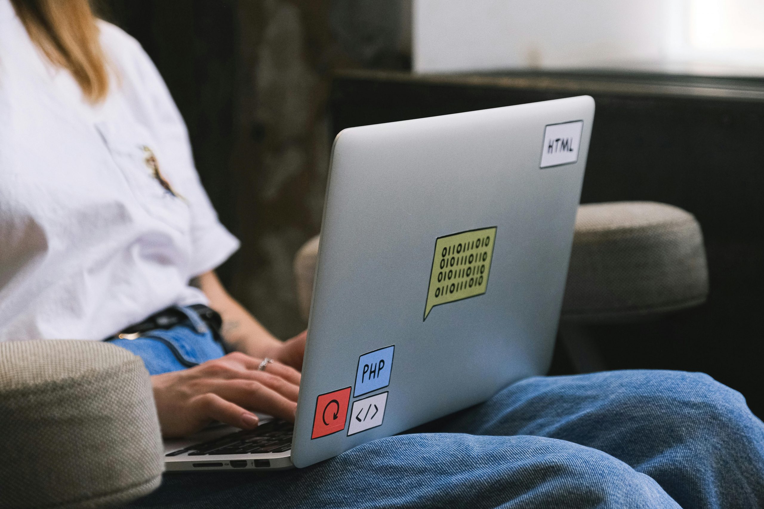 Person typing on a laptop with coding stickers, symbolizing remote work and freelancing.