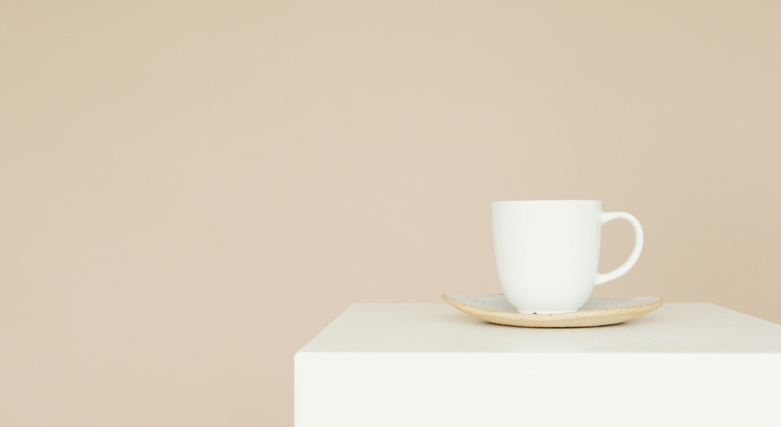 Elegant white coffee cup and saucer on a neutral background, perfect for branding or advertising.